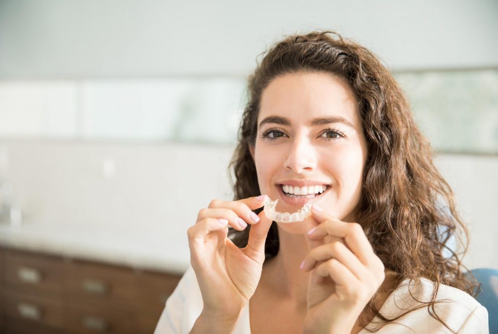 Patient holding orthodontic retainers in dental clinic