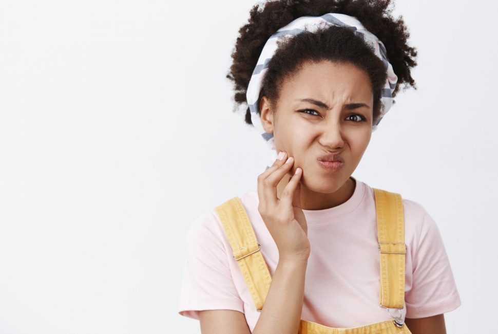 Unhappy woman holding jaw in pain from bruxism